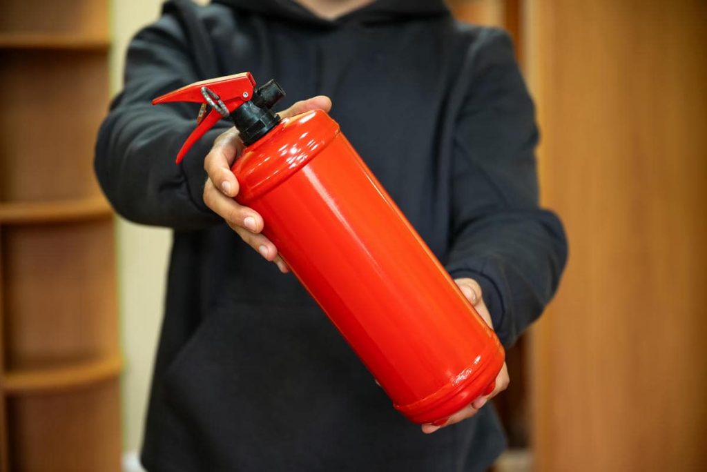 A man is holding a fire extinguisher in the office. The concept of fire safety