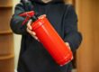 A man is holding a fire extinguisher in the office. The concept of fire safety